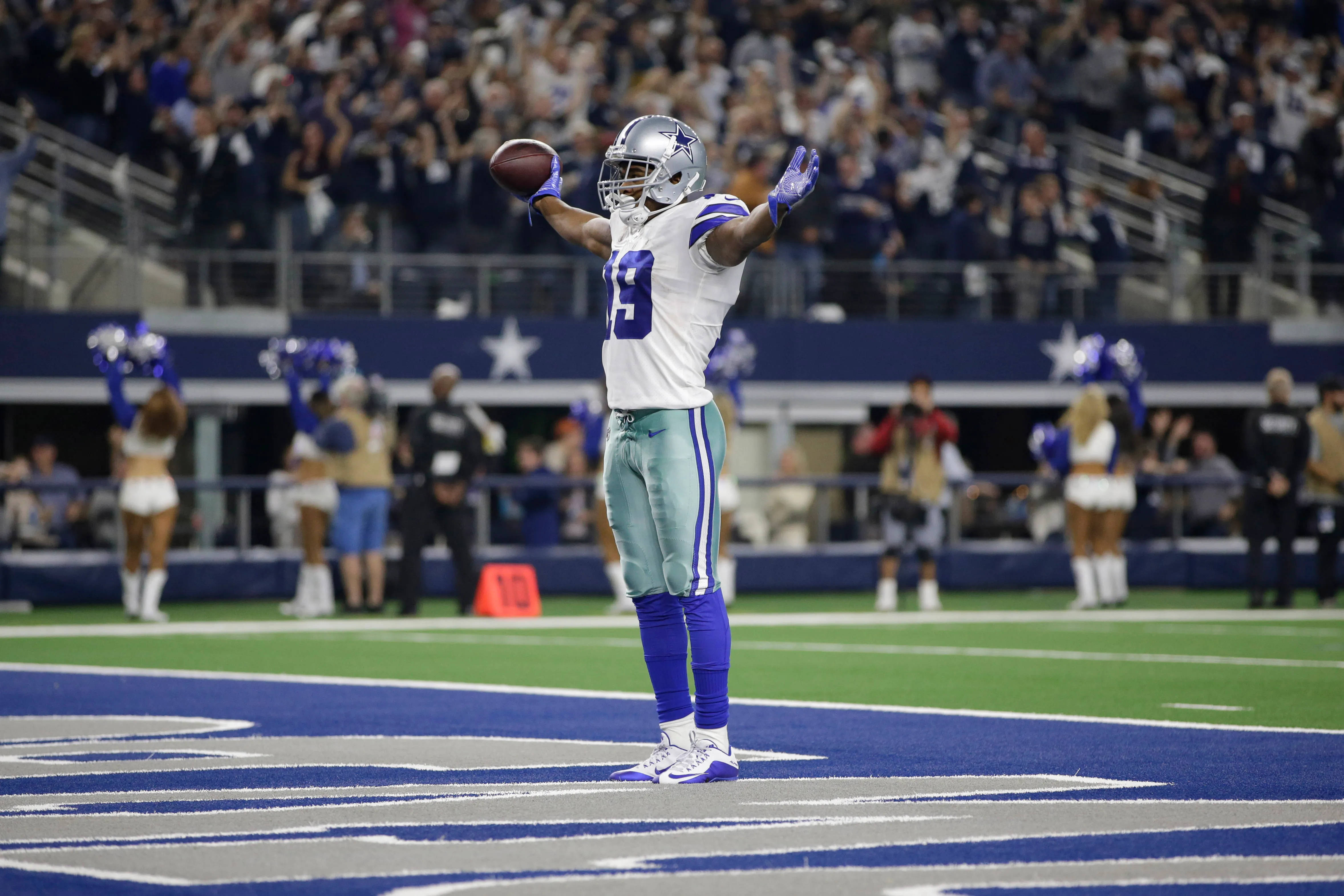Stadium 桌布 壁紙 — 達拉斯牛仔隊19號球員在體育場燈光下高舉雙臂持球慶祝達陣。