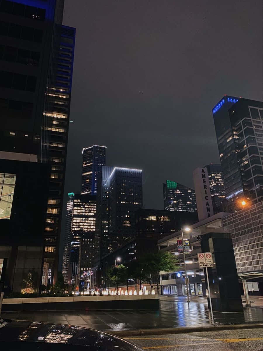 達拉斯縣壯麗景觀 壁紙 — 雨濕的夜晚城市街道，高聳的摩天大樓在黑暗的天空下閃耀。