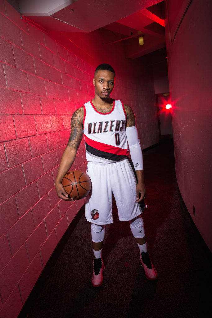 身穿 Blazers 球衣的籃球運動員在紅色燈光走廊中手持籃球。