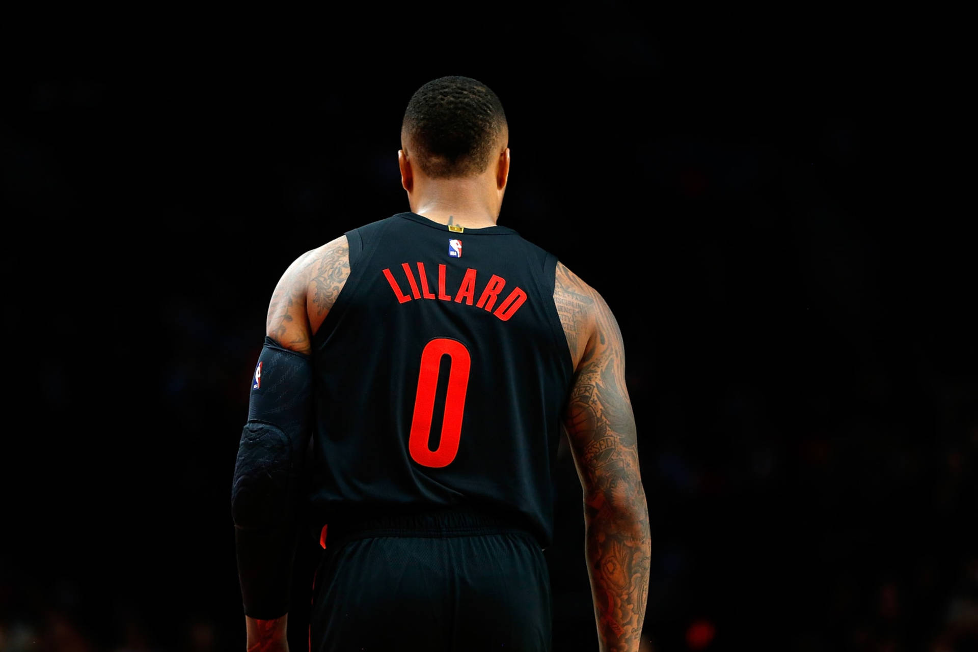 籃球運動員 Damian Lillard 身穿黑色球衣，紅色零號，背對鏡頭。