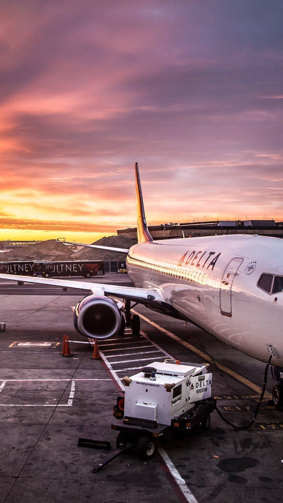 達美航空飛機在色彩繽紛的日落時分停在機場停機坪上。