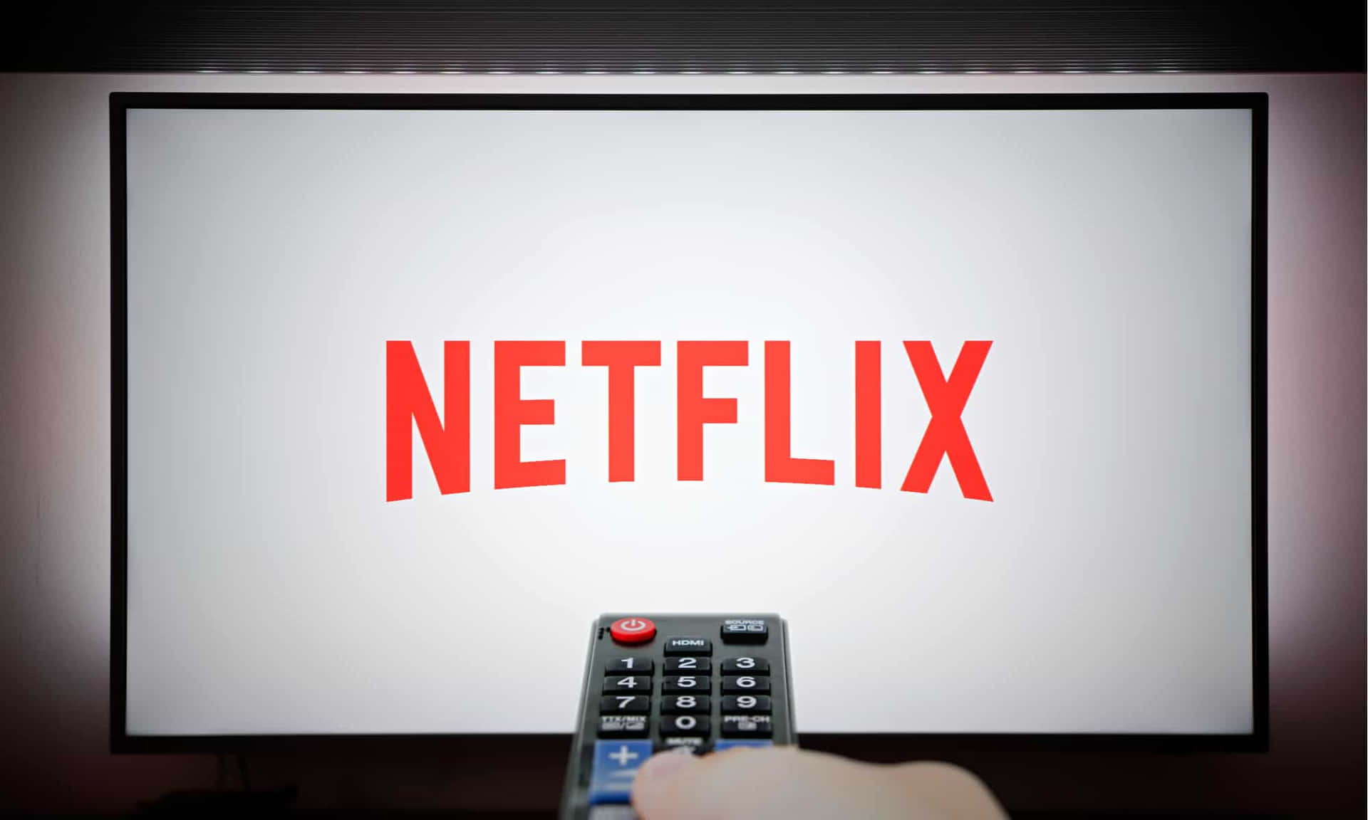 手拿遙控器指向顯示Netflix標誌的電視。