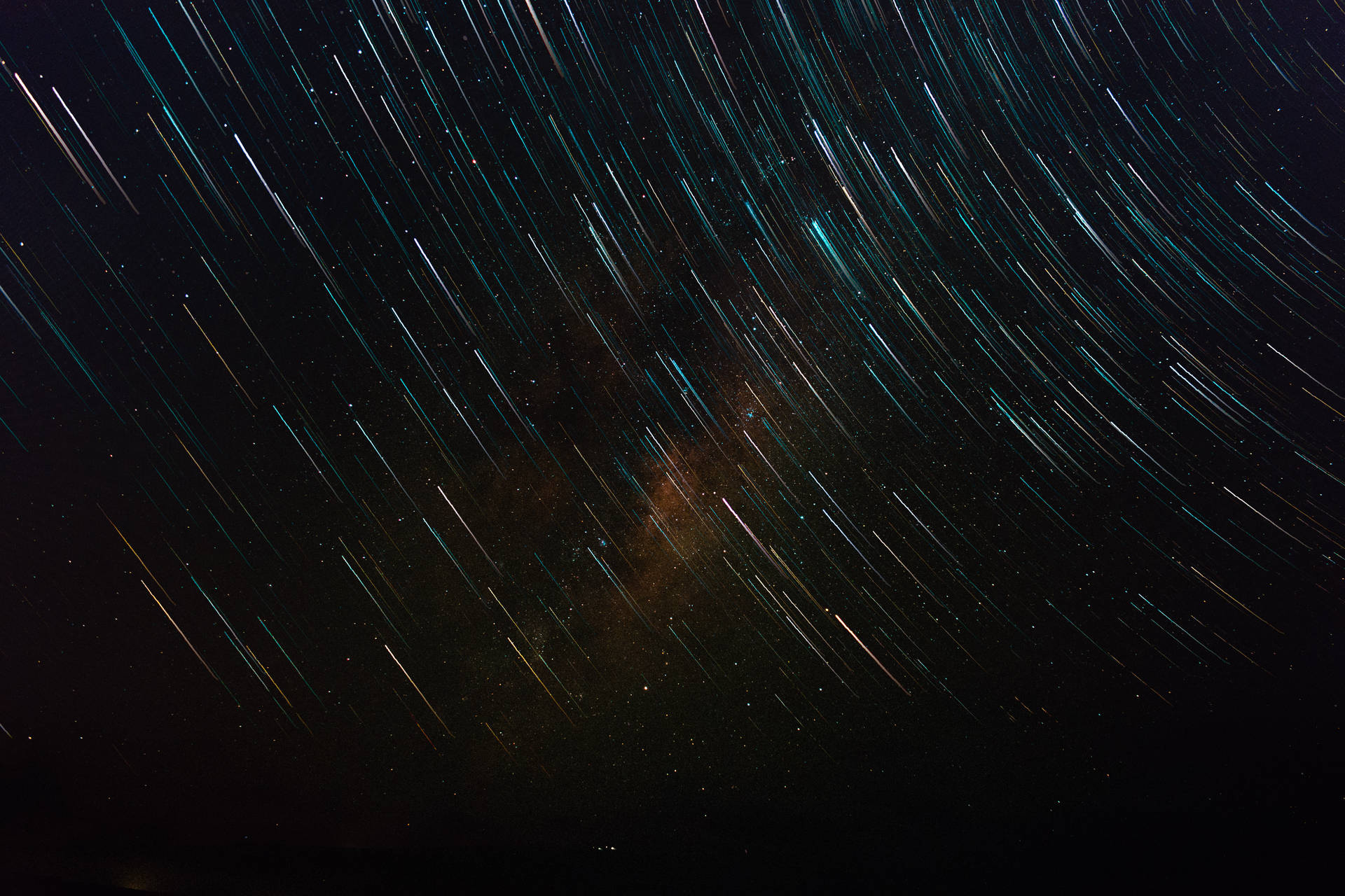在黑暗的夜空中，天體星軌圍繞著發光的星雲旋轉。