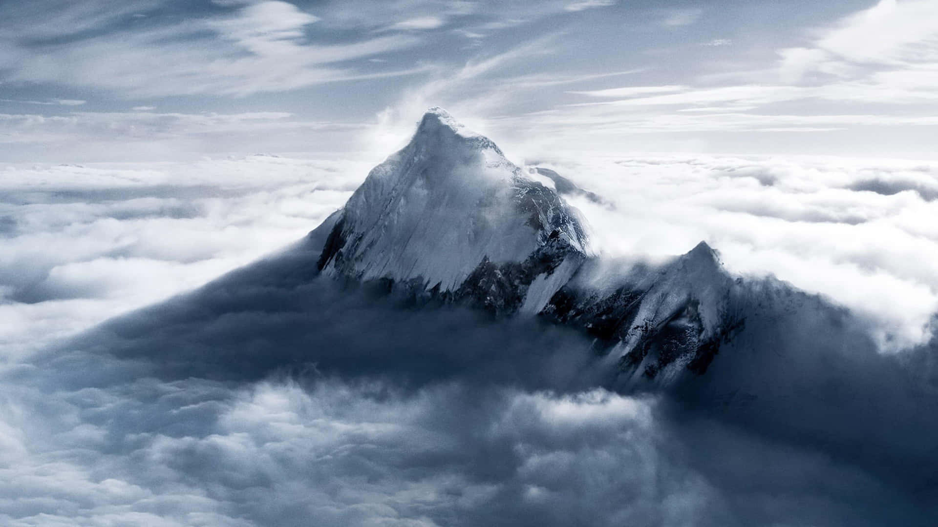 白雪覆蓋的山峰聳立在厚厚的雲層之上。