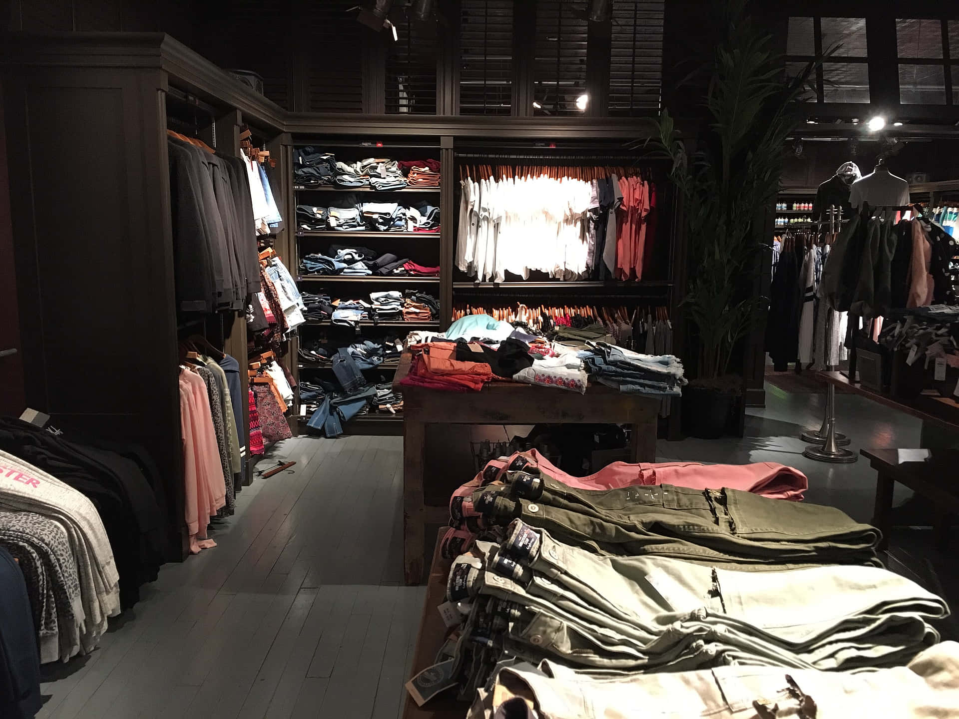 一間時尚服裝店，在溫暖燈光下展示著掛架和成堆的衣物。