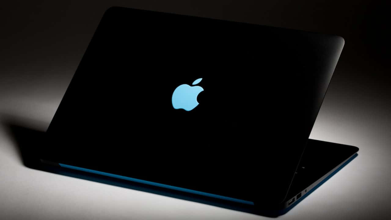 工作室燈光下帶有發光藍色Apple標誌的黑色手提電腦