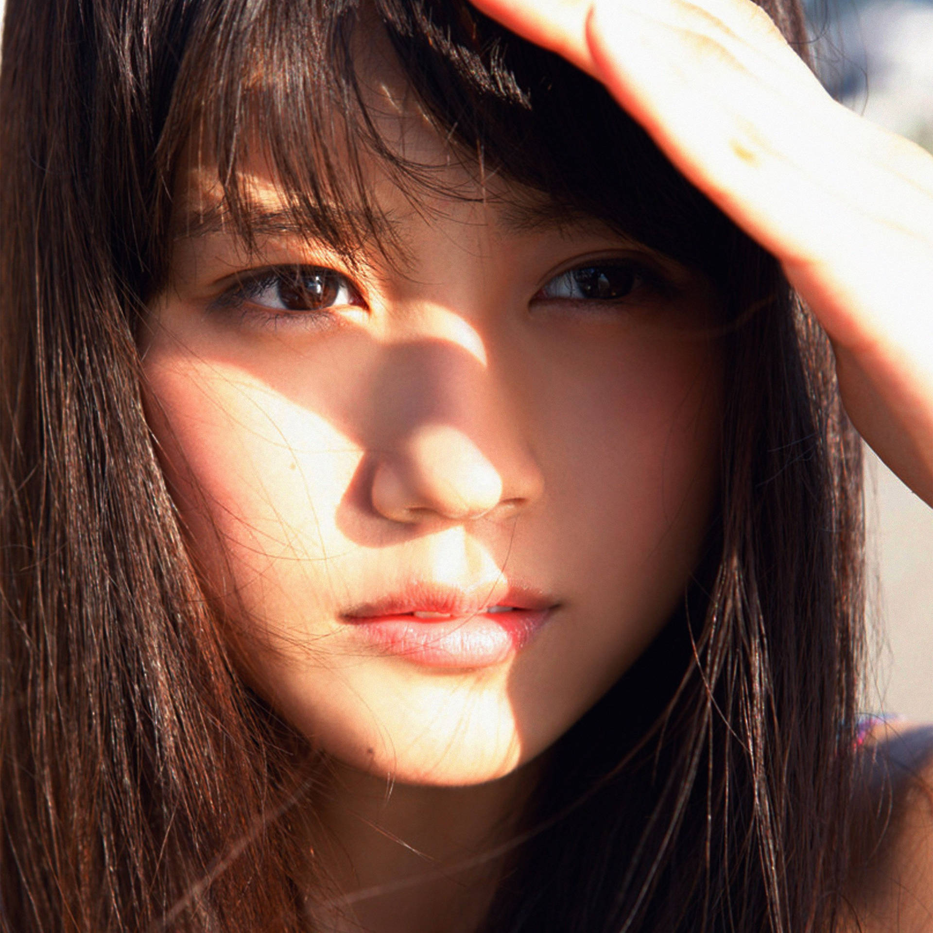 年輕女子舉手遮擋刺眼陽光。