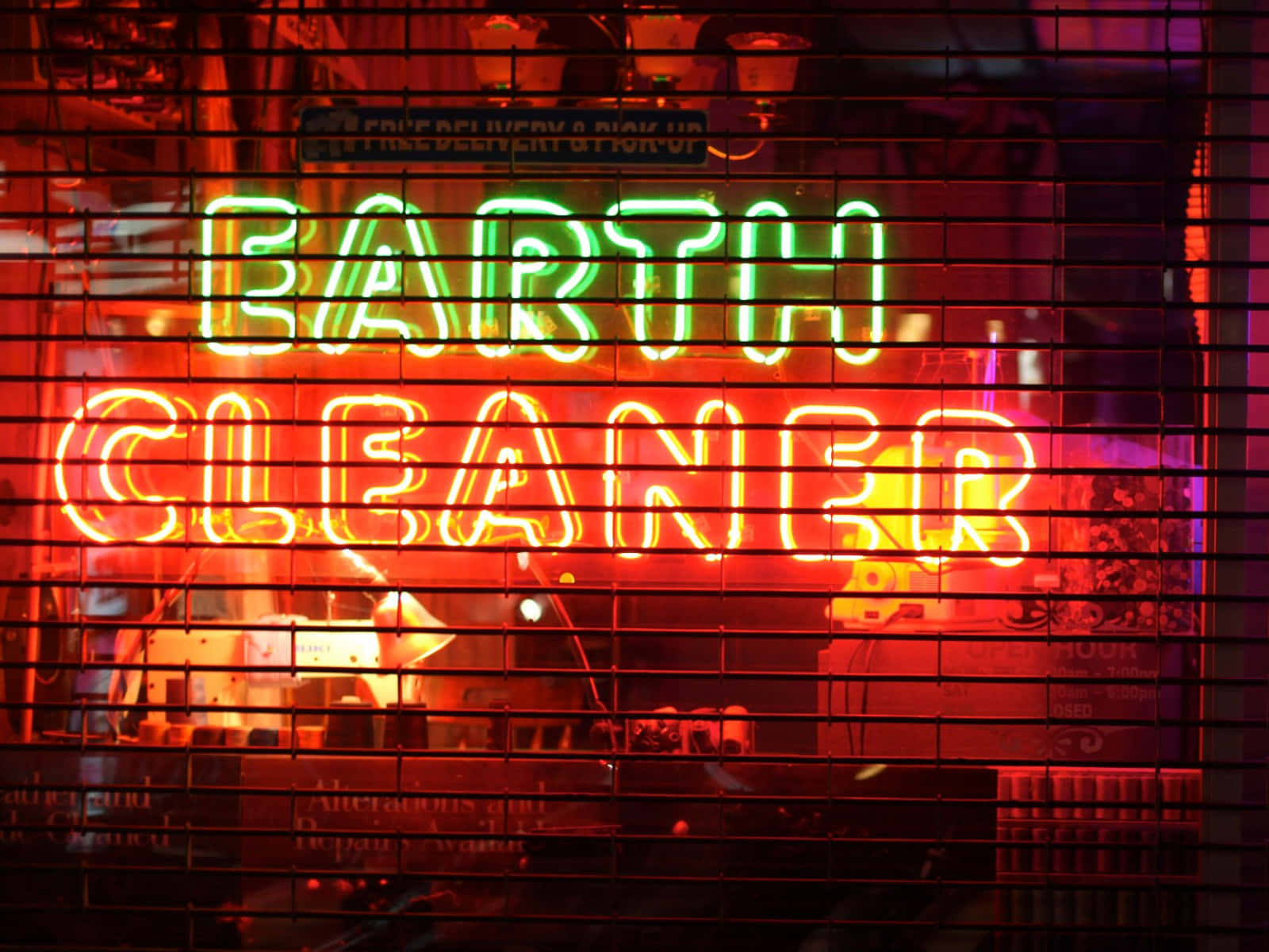 夜晚金屬格柵後方的霓虹燈牌，寫著Earth Cleaner。