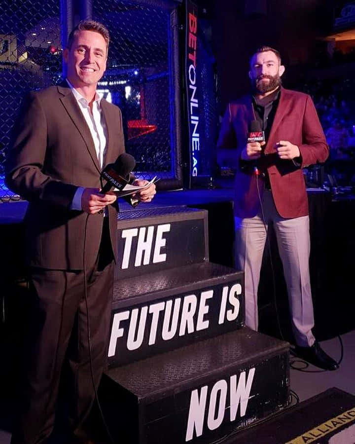 兩位UFC評論員在舞台上，身後有「The Future Is Now」階梯。