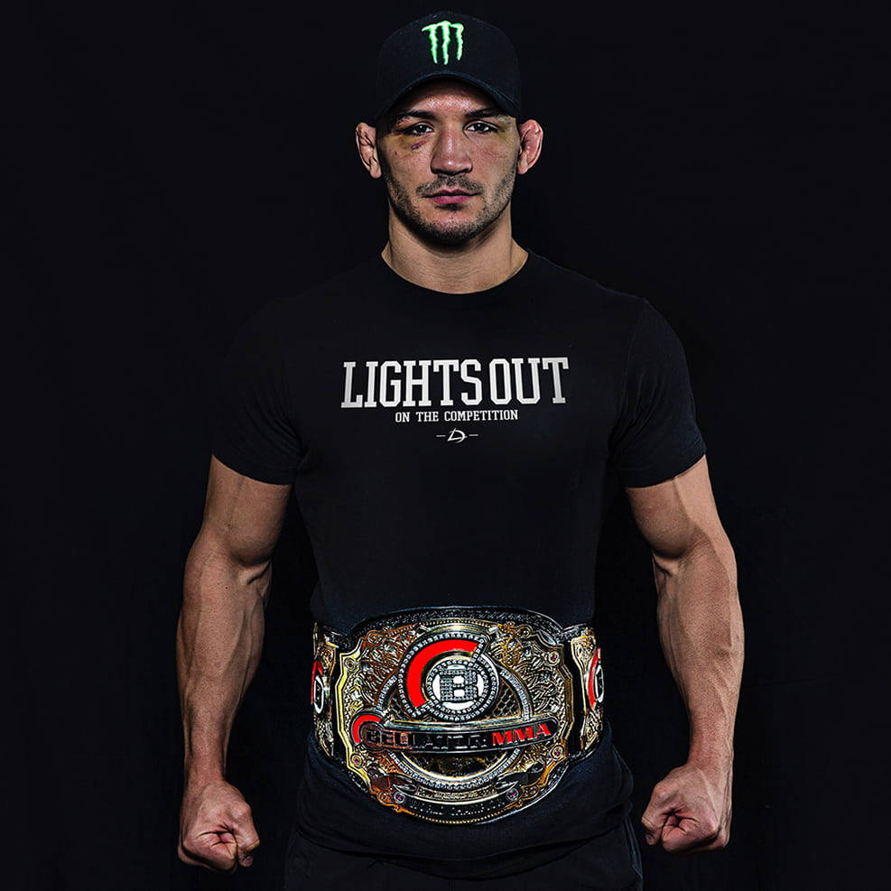 一位MMA冠軍戰士佩戴冠軍腰帶，身穿印有「Lights Out」字樣的黑色T恤。