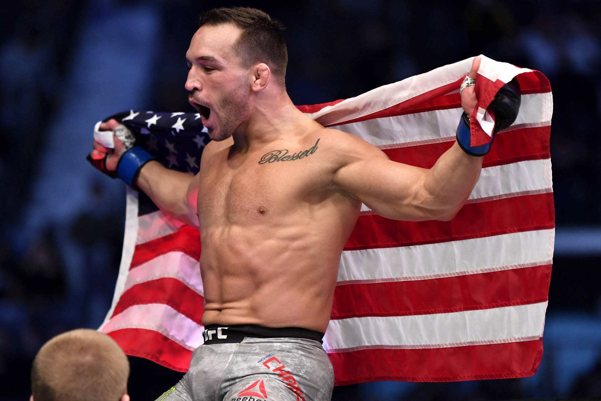 一位赤裸上身的MMA拳手手持美國國旗慶祝勝利。