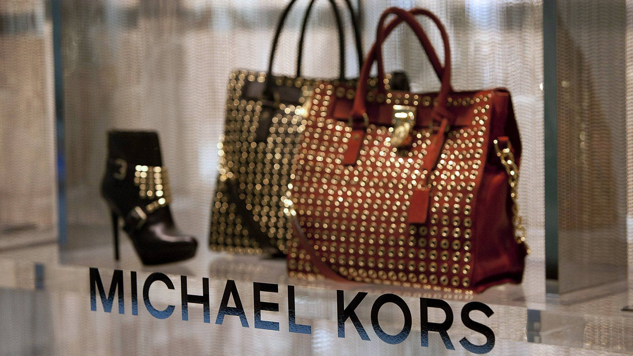 邁克高斯玻璃展櫃展示 壁紙 — 奢華 Michael Kors 手袋和靴子在時尚的零售櫥窗展示中閃耀著金色飾釘。
