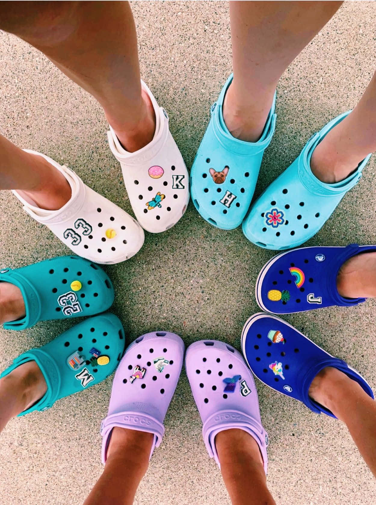 六個人的腳穿著裝飾過的Crocs鞋，在路面上排成一個圓圈。