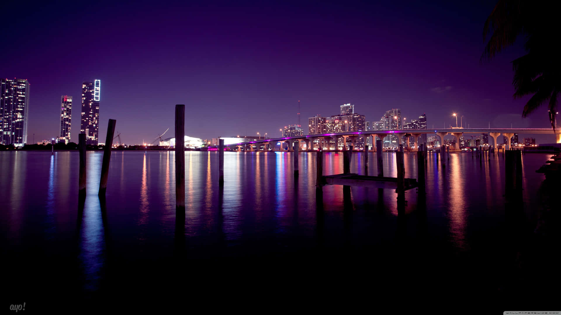 夜晚城市景觀，發光的建築物和橋樑倒映在水中。