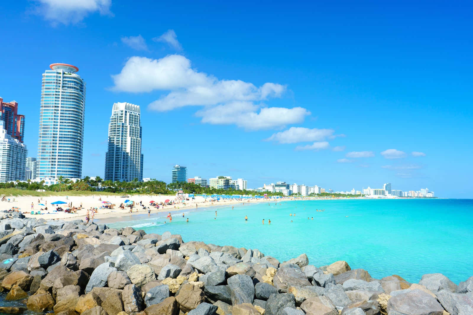 陽光明媚的海灘，碧綠的海水，背景是現代化的城市天際線。