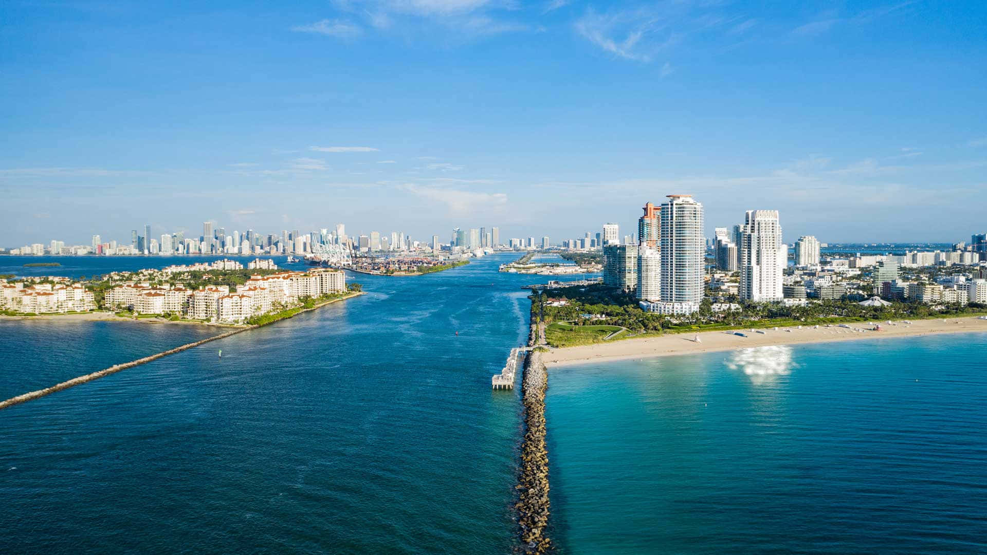 邁阿密 桌布 壁紙 — 邁阿密海灘的鳥瞰圖，在清澈的藍天下，碧綠的海水將沙灘與高聳的摩天大樓分隔開來。