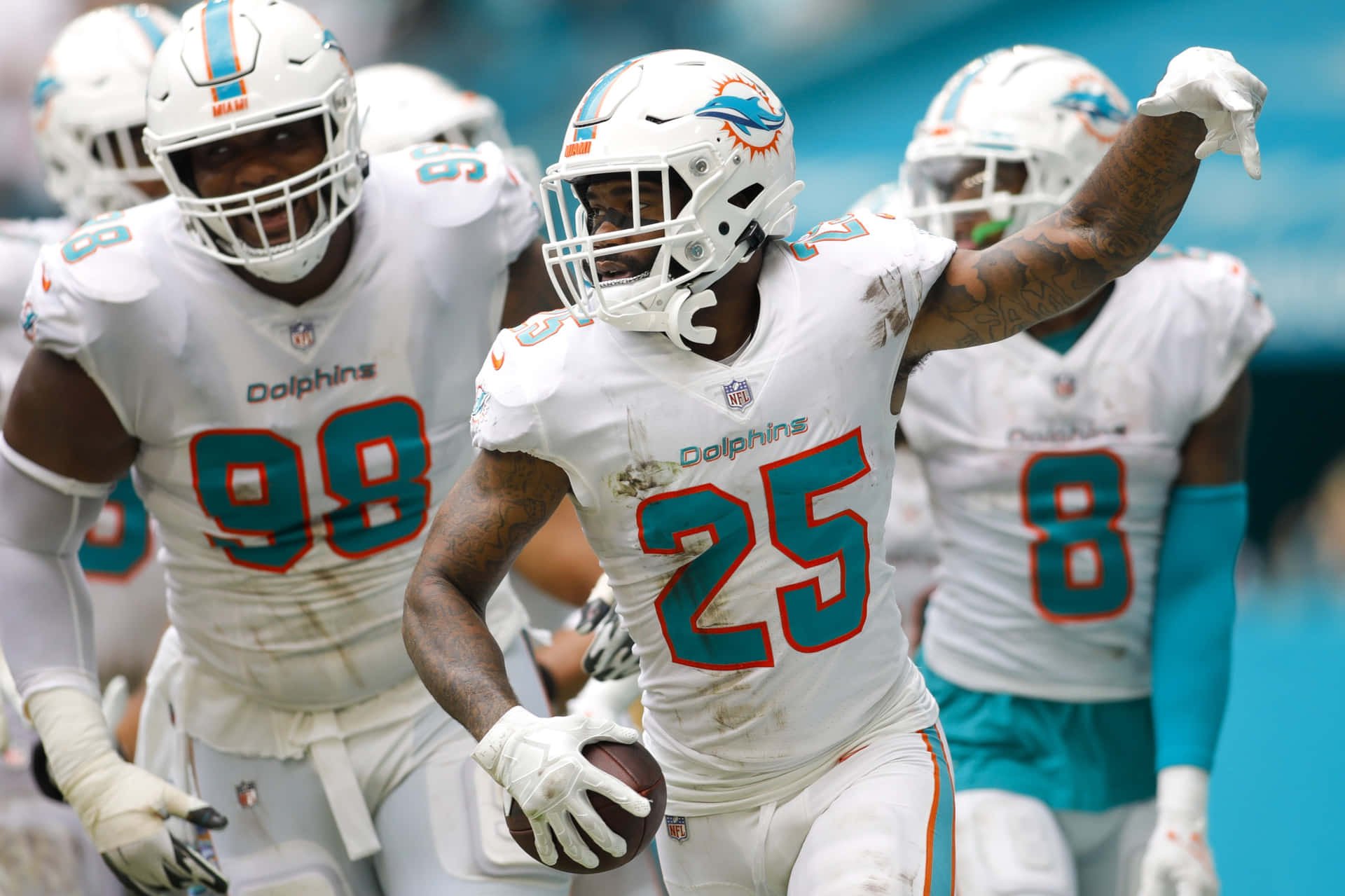邁阿密海豚隊與Xavien Howard 壁紙 — 邁阿密海豚隊美式足球員身穿白色球衣在球場上慶祝，其中一人手持足球。