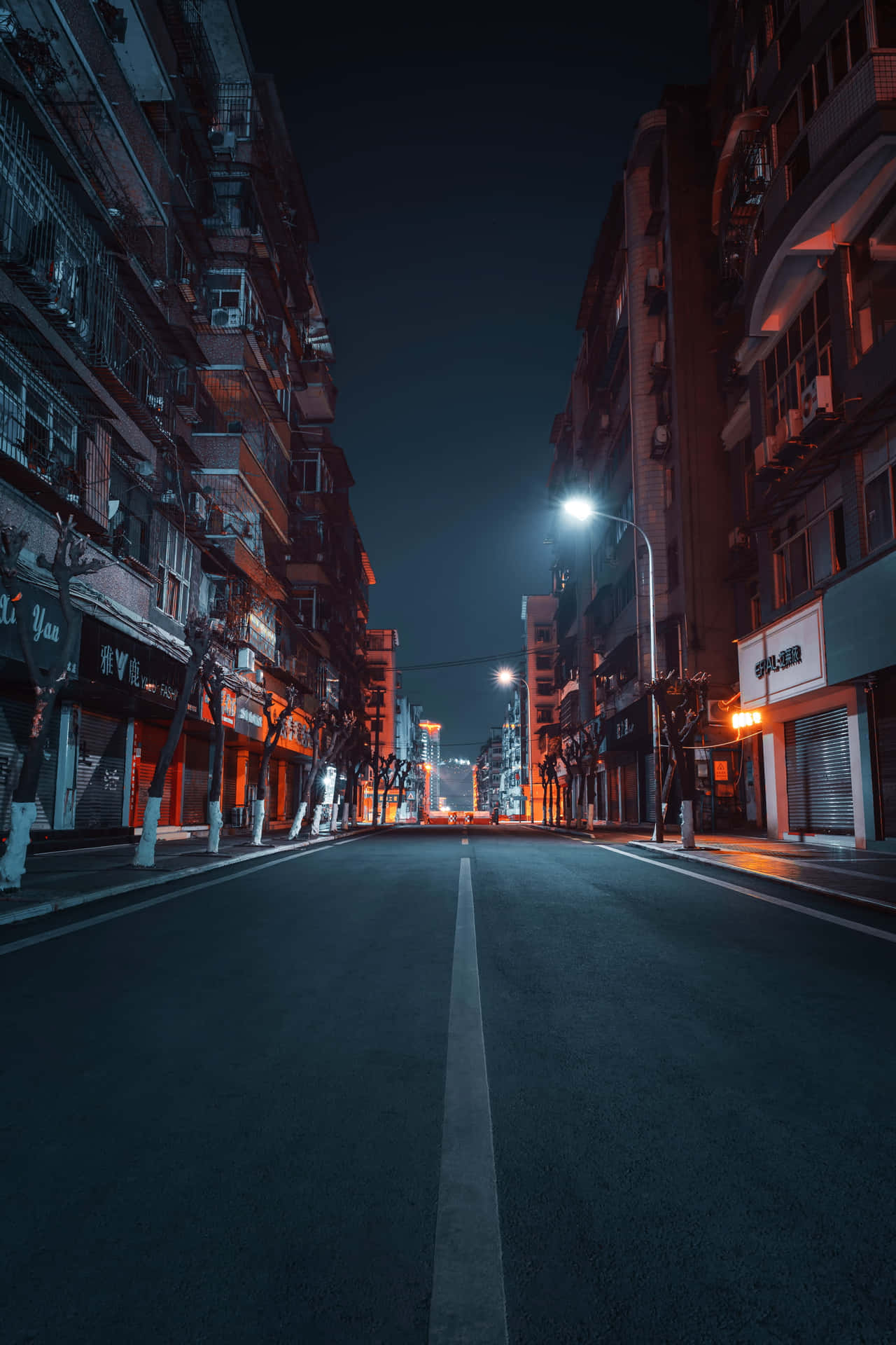 夜晚空無一人的城市街道，有發光的街燈和高樓大廈。