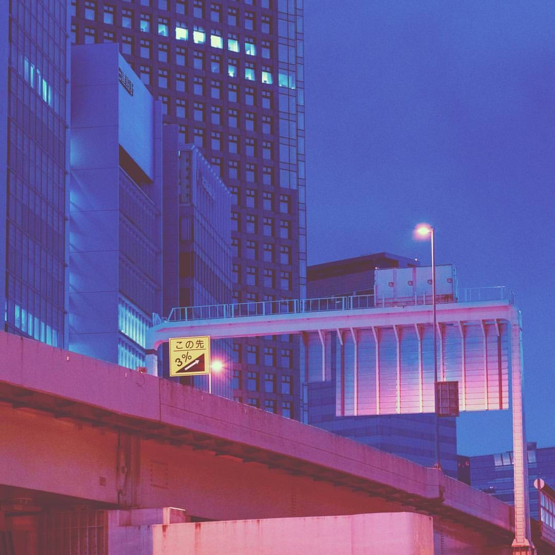 黃昏時分粉紅和藍色照亮的城市高速公路，背景有高樓大廈。