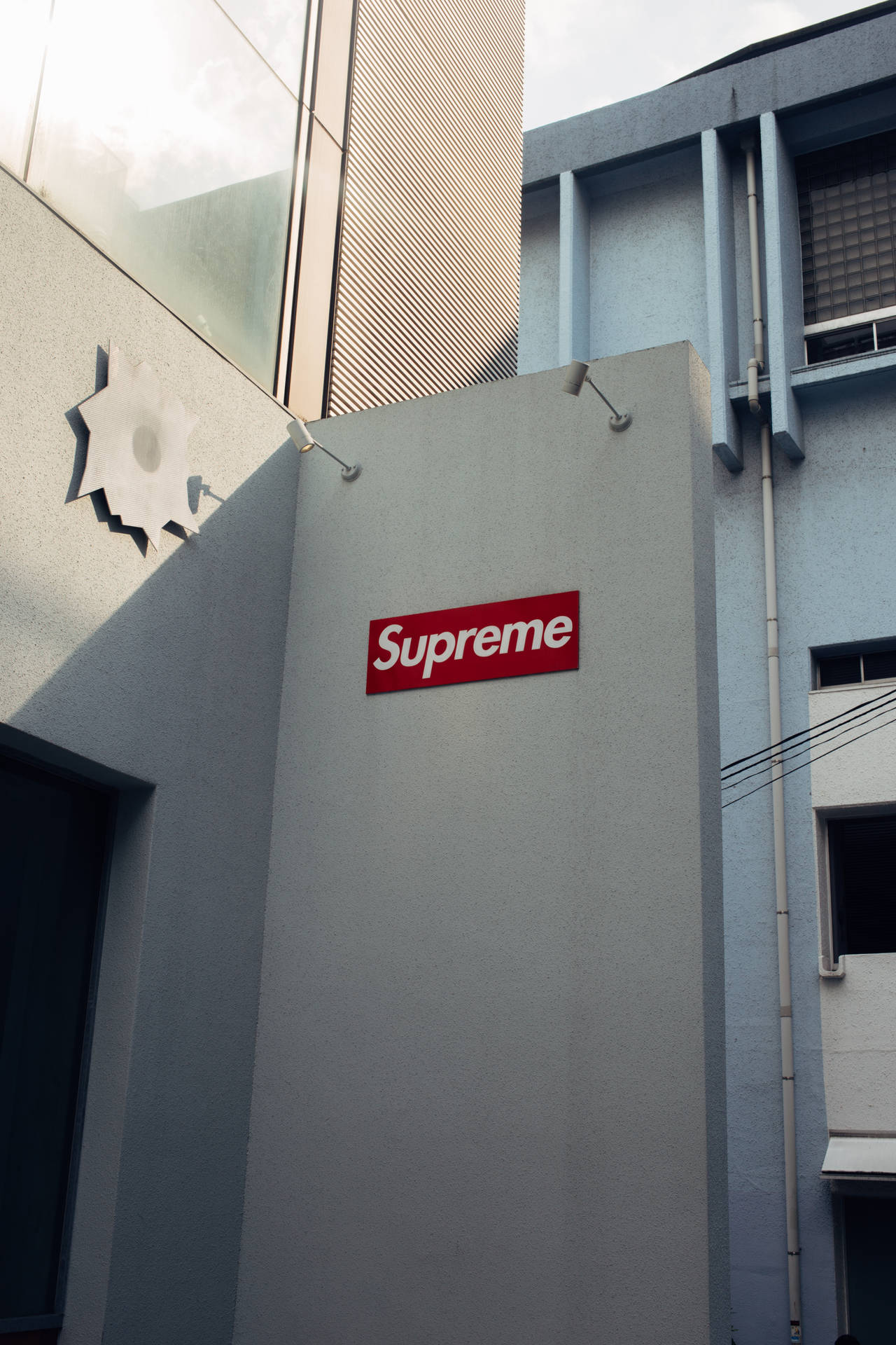灰色城市建築牆上的紅色Supreme標誌。