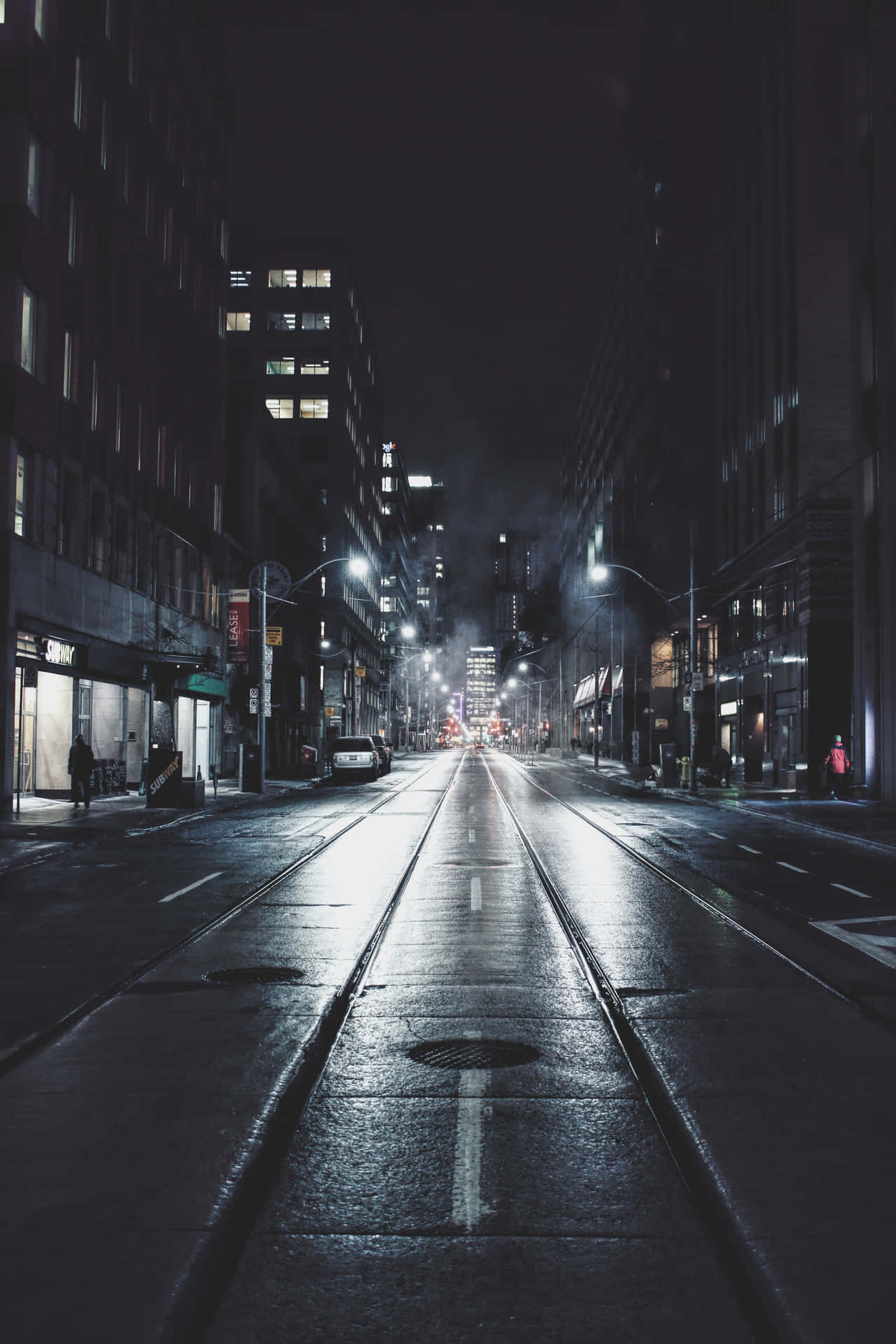 夜晚潮濕的城市街道，反射著街燈和建築物窗戶。