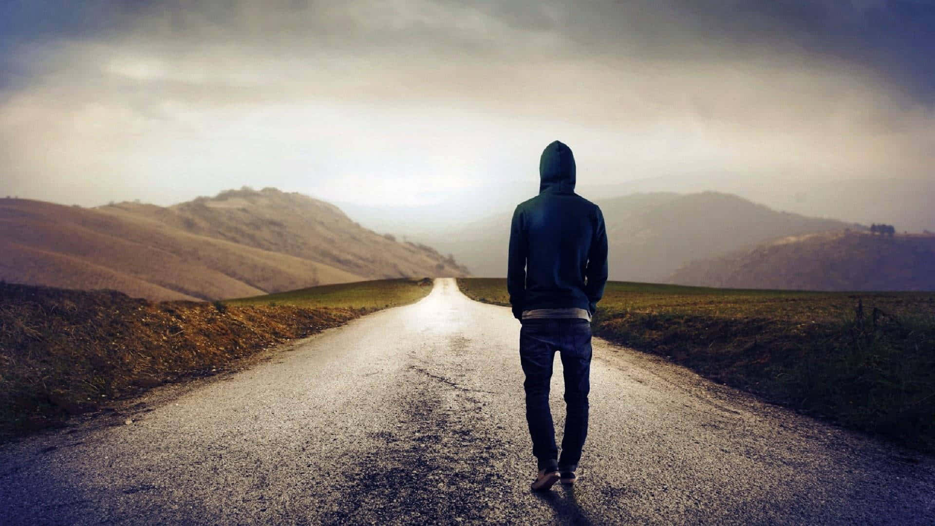 黃昏時分，一個人穿著連帽衫獨自走在鄉間小路上。