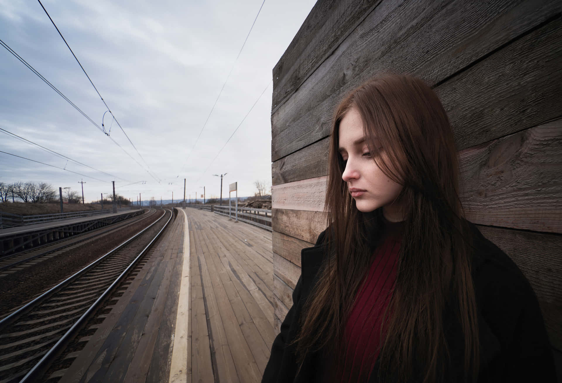 年輕女子站在火車月台上，帶著若有所思的表情望向遠方