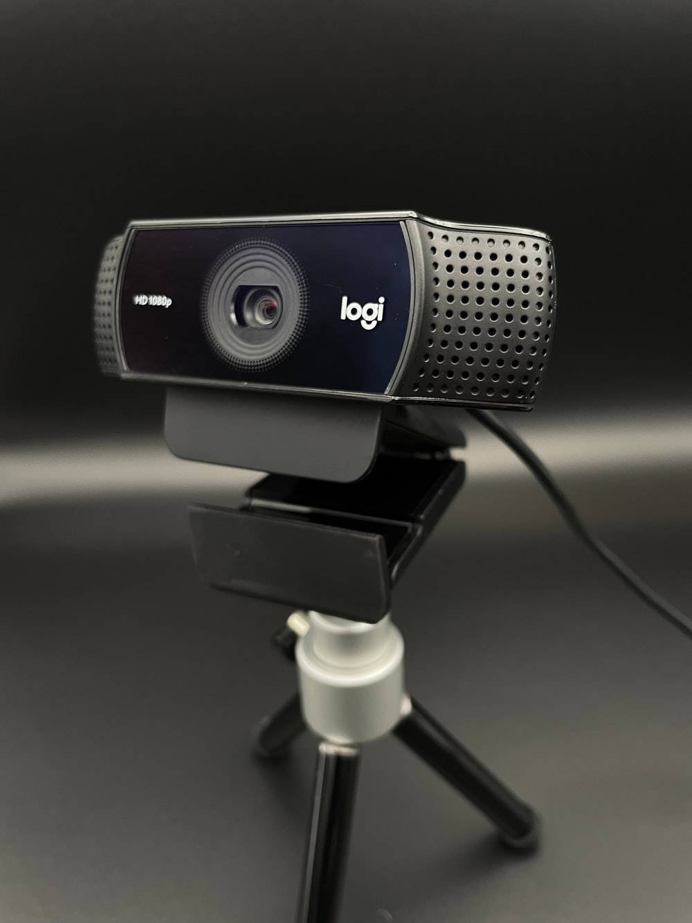 黑色Logitech網絡攝像頭在三腳架上，深色背景