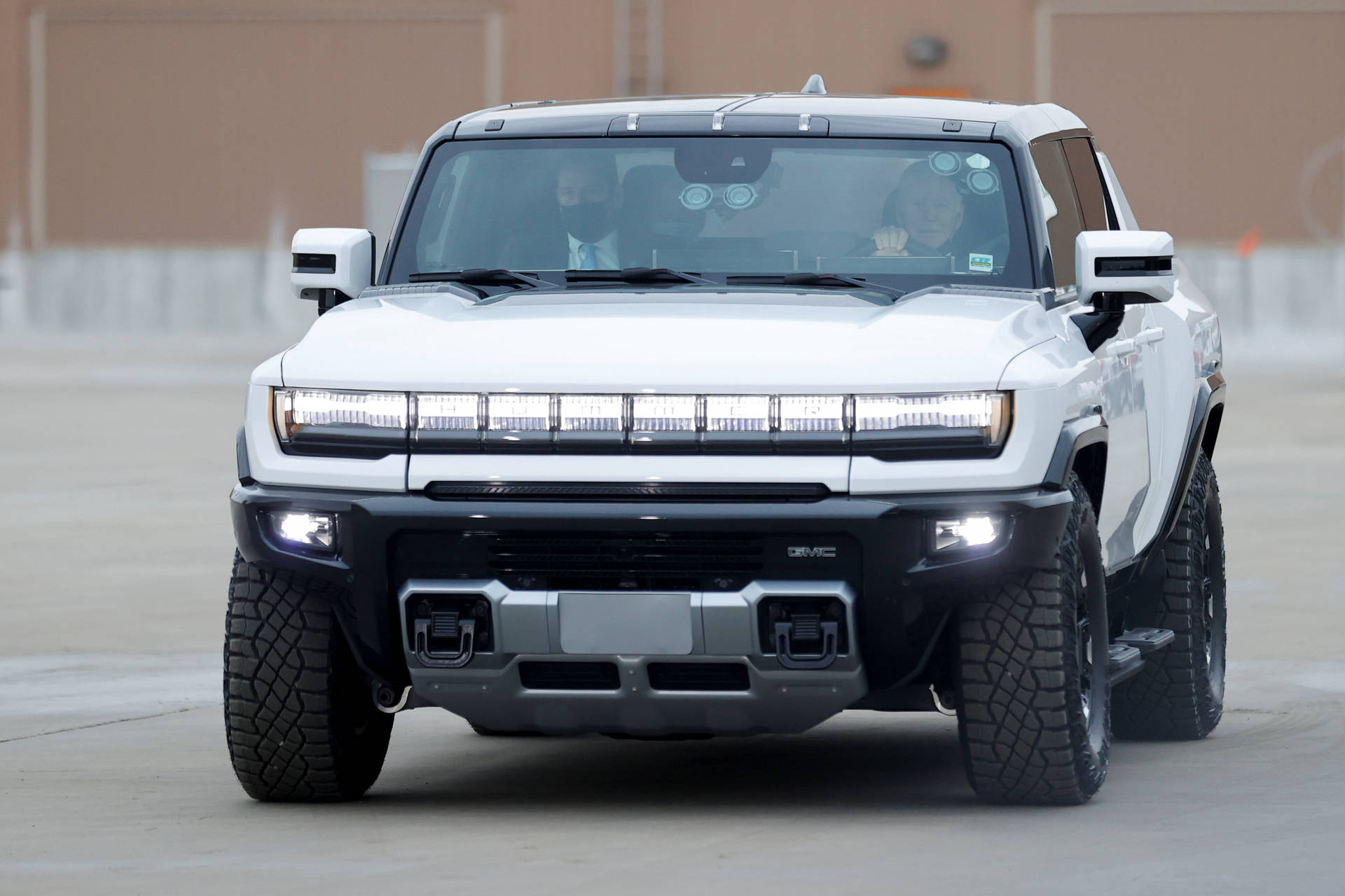 白色GMC Hummer EV SUV，在混凝土表面上頭燈亮起。