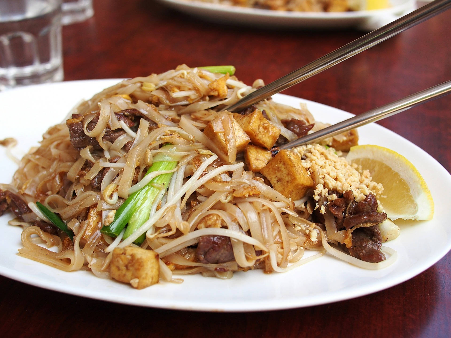 白碟上放有炒米粉，配以豆腐、牛肉及青檸裝飾。
