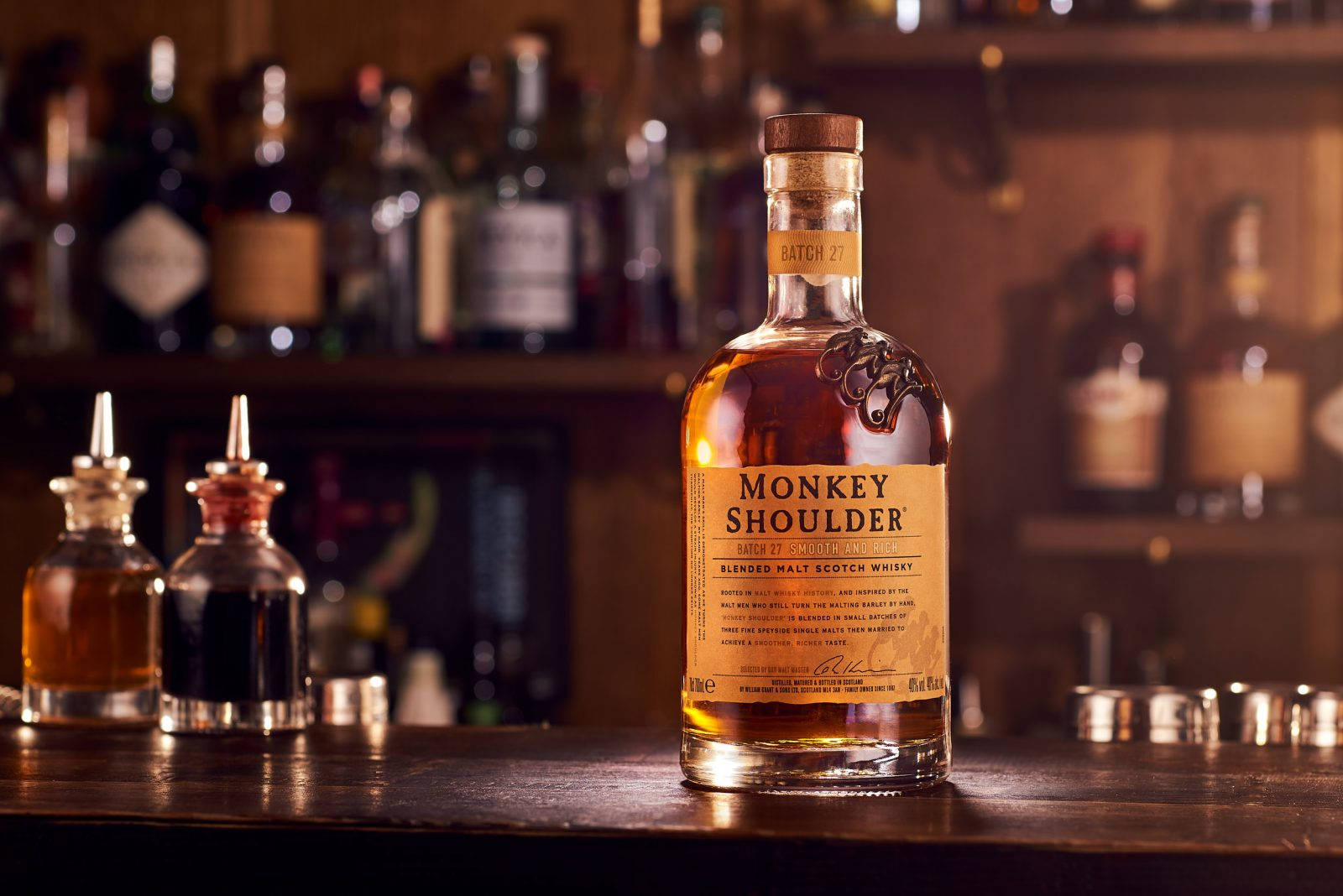 Monkey Shoulder威士忌酒瓶與調酒器和其他烈酒一同擺放在吧檯上。