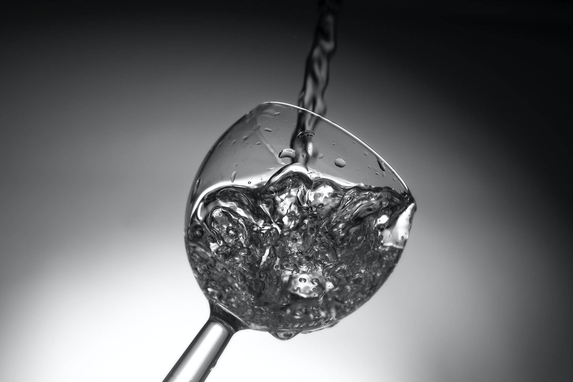 水倒入玻璃杯中，在黑白中產生氣泡和水滴。