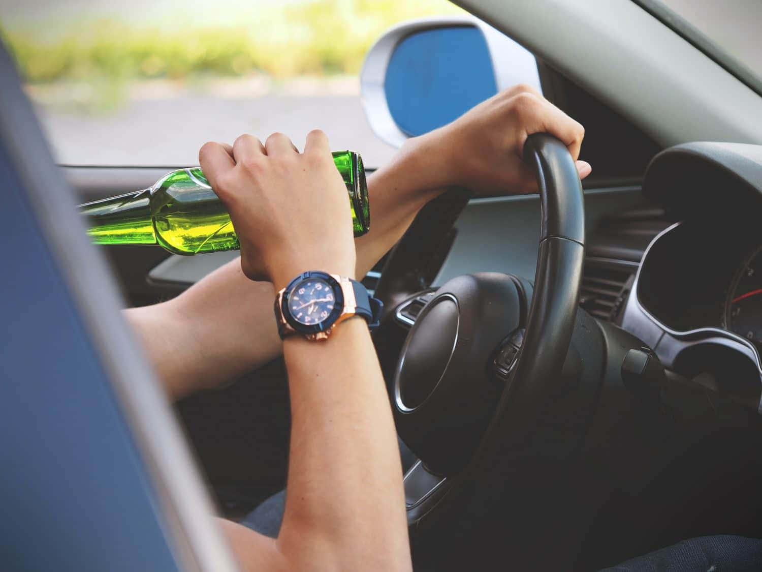 駕駛汽車的人拿著綠色啤酒瓶戴著手錶