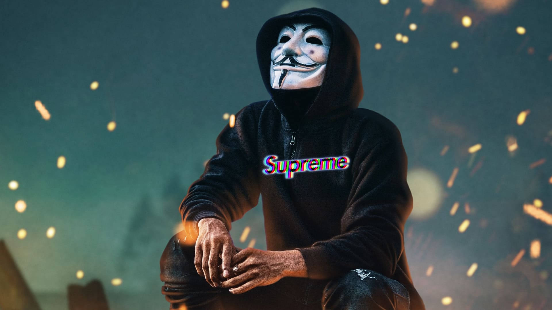 酷 Supreme 匿名餘燼 壁紙 — 一名身穿黑色連帽衫、戴著蓋伊·福克斯面具的人坐在深藍綠色背景中閃爍的餘燼之間。