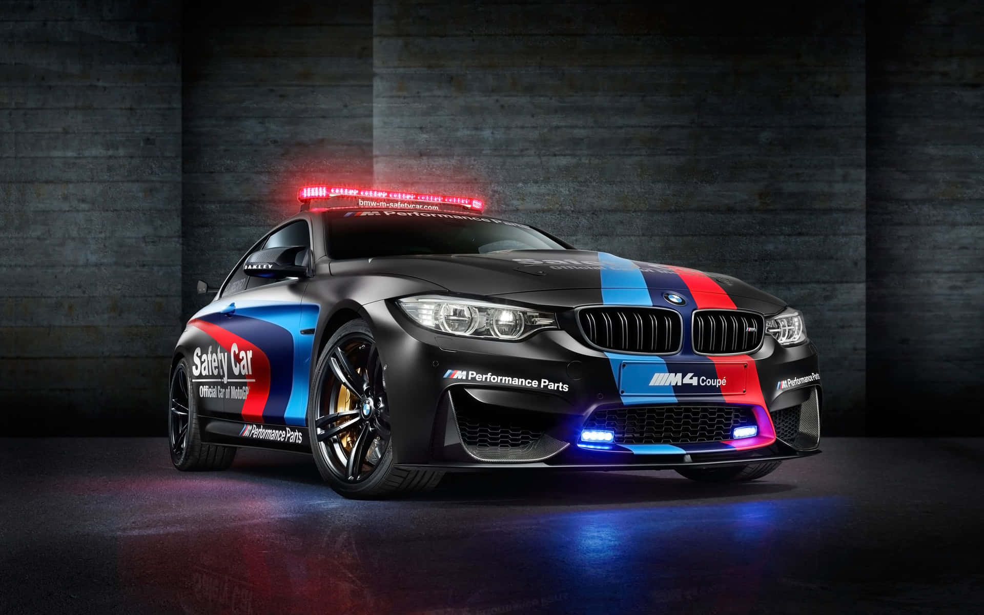 黑色BMW M4 Coupe安全車，帶有紅藍條紋和閃燈，在黑暗的車庫中。