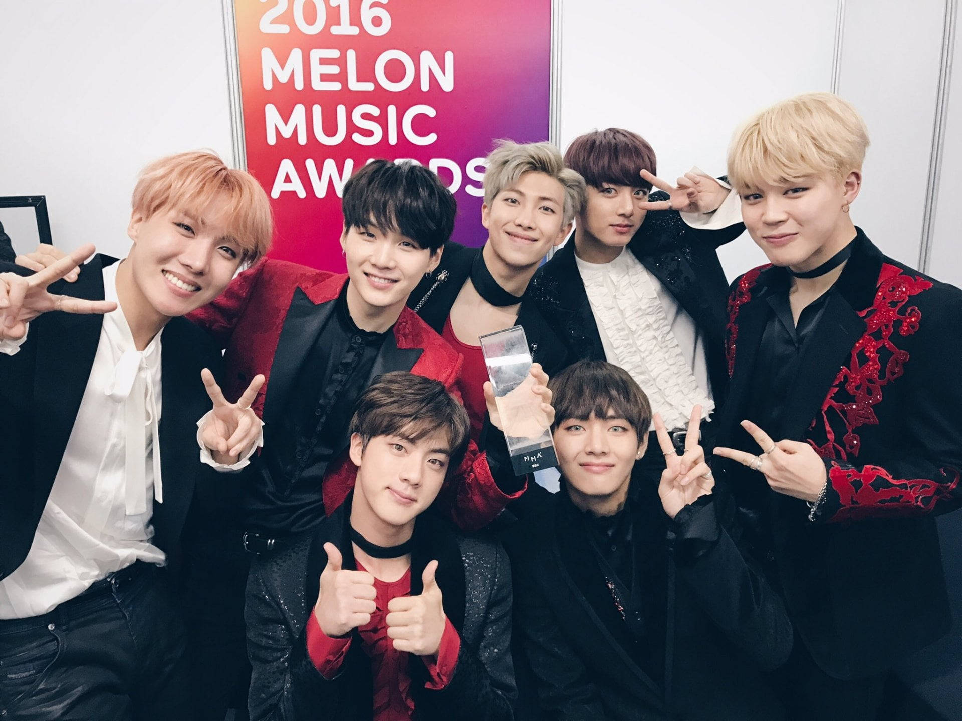 七位K-pop偶像在2016年Melon Music Awards上手持獎盃擺姿勢。