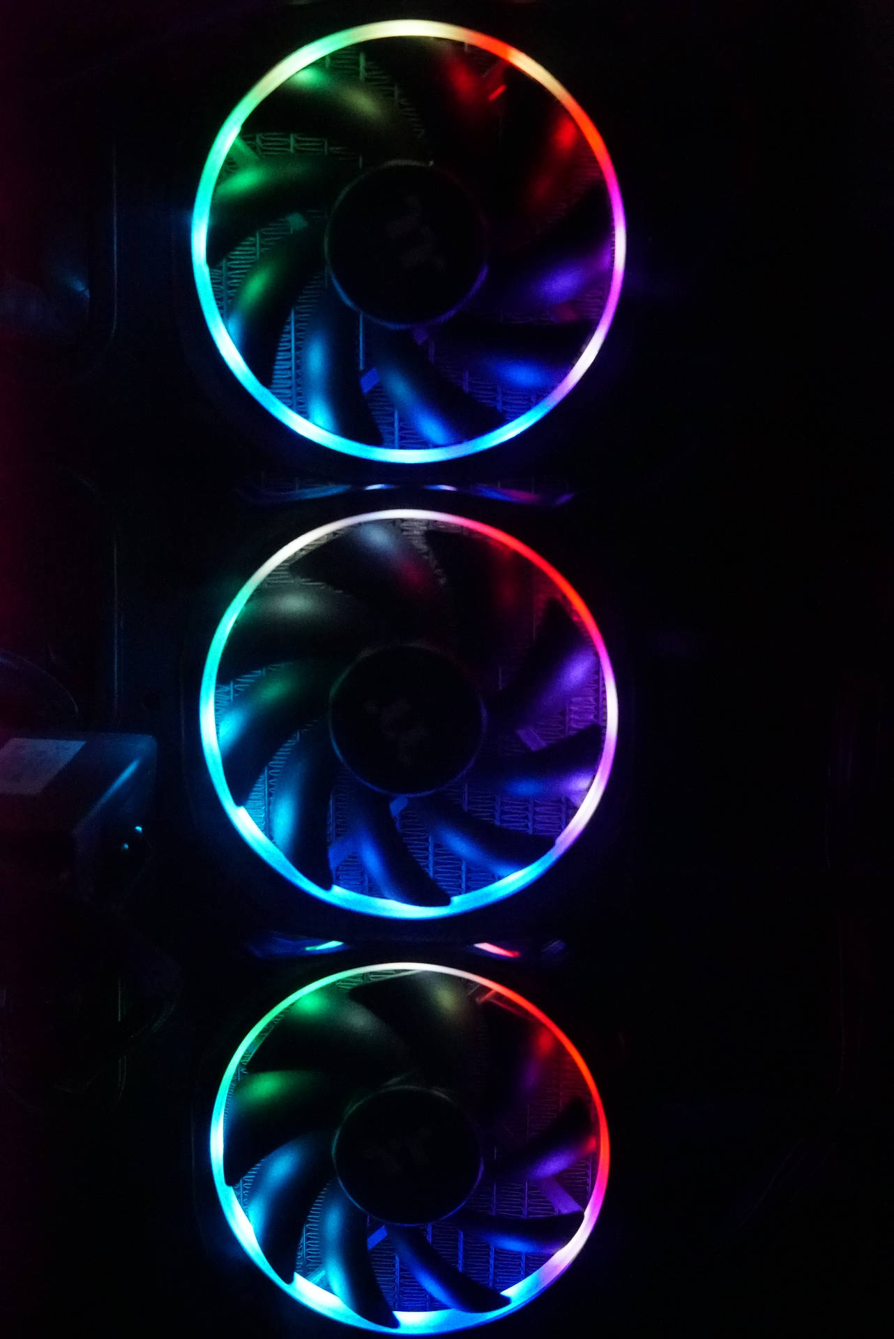 三個RGB電腦機箱風扇在黑暗中發出彩虹光芒。