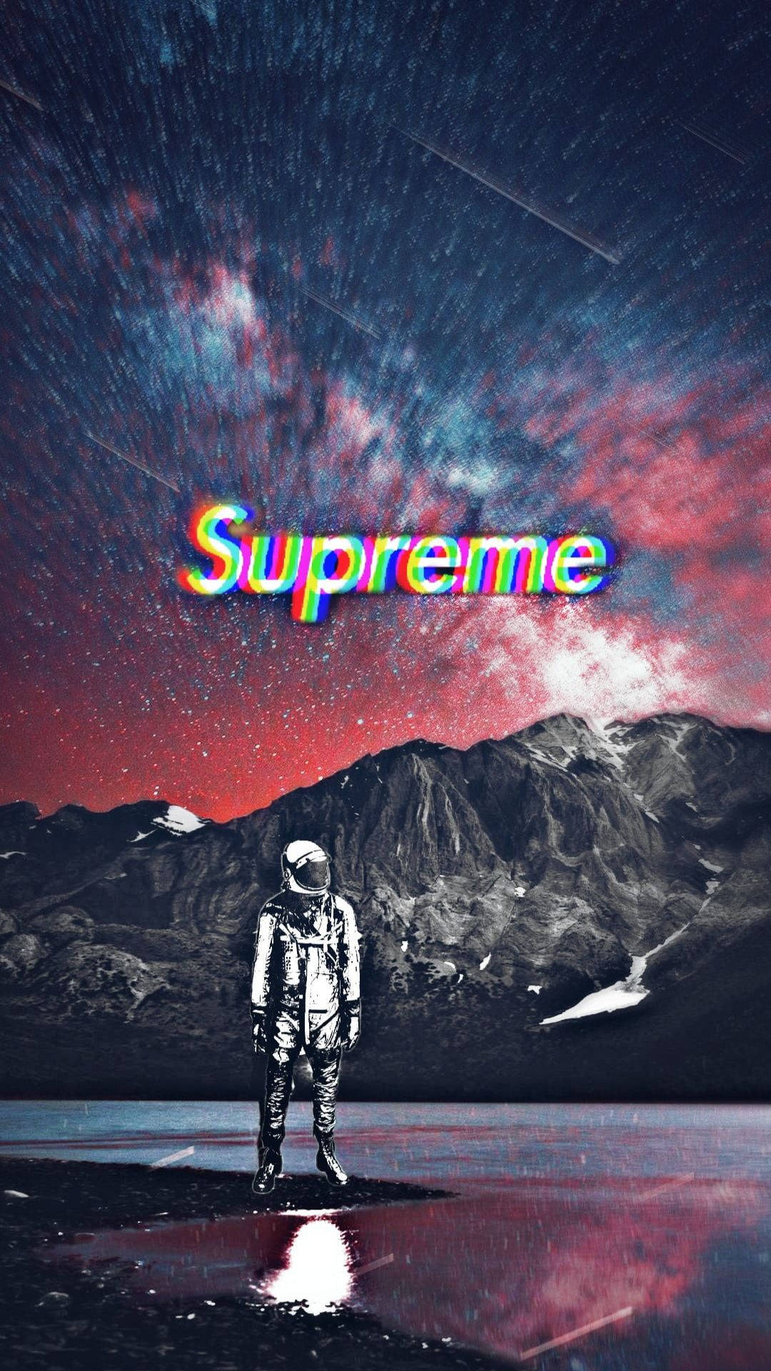 酷炫Supreme宇航員山景 壁紙 — 一名太空人獨自站在反射湖面上，前方是積雪的山脈，下方是充滿活力的星空，而「Supreme」這個詞以故障彩虹文字發光。