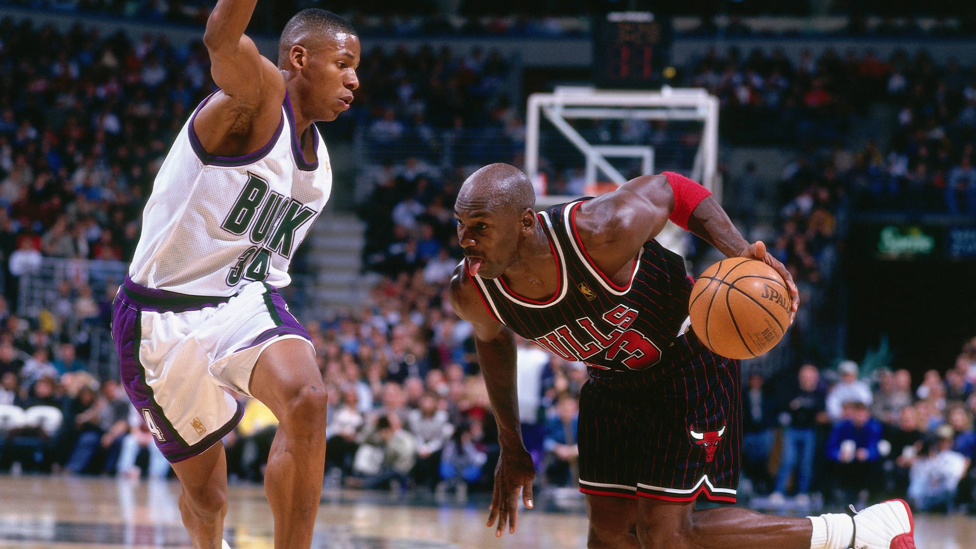 酷炫喬丹對決艾倫1996年NBA 壁紙 — 米高佐敦在擠滿觀眾的場館內低身運球，同時被密爾沃基公鹿球員緊密防守。