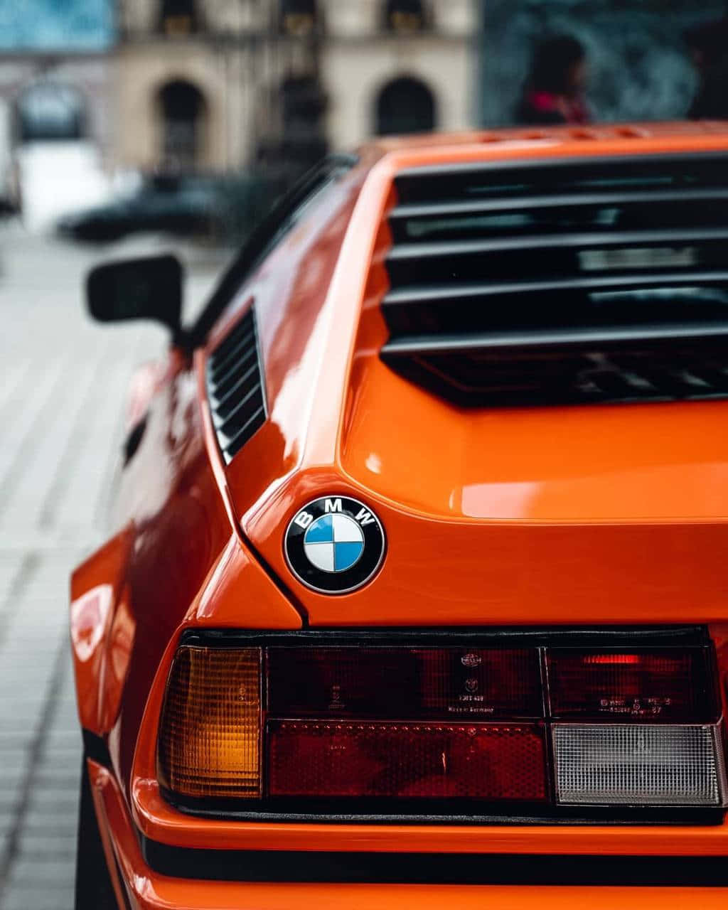 橙色BMW M1跑車城市街道後視圖