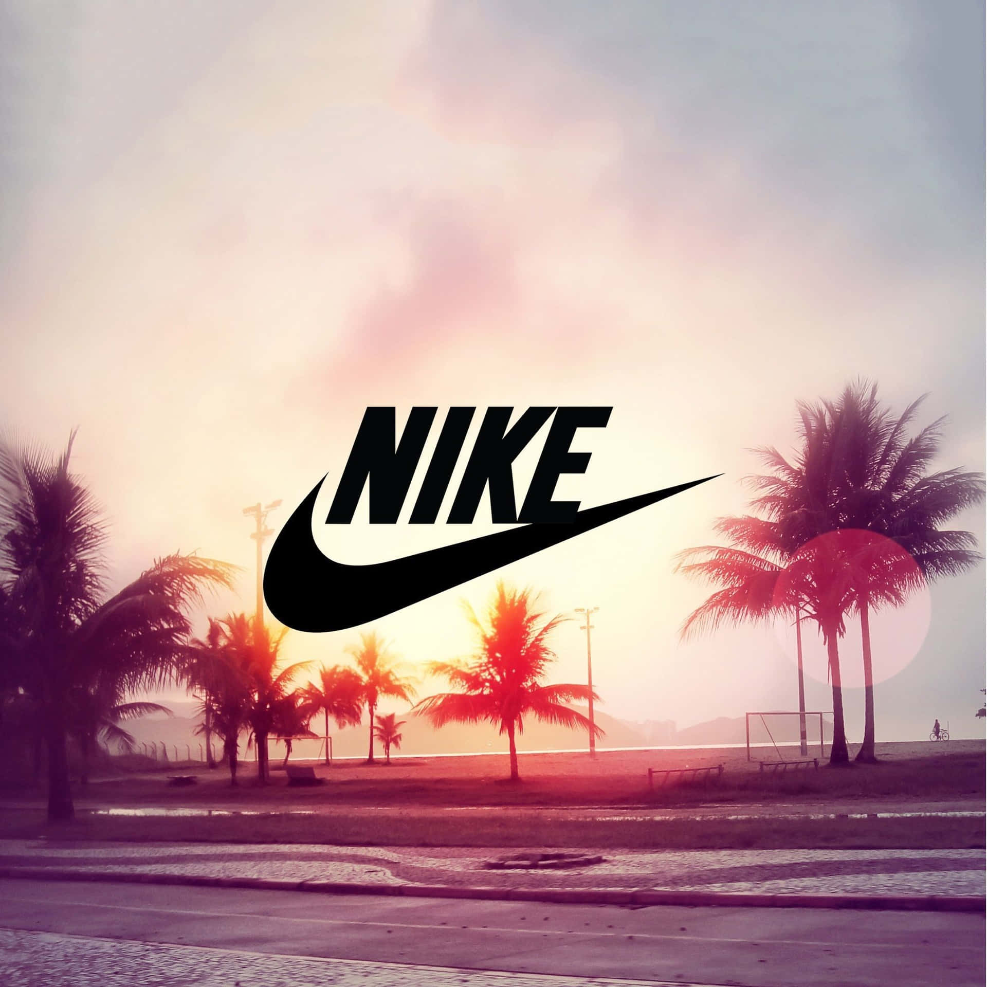 海邊小路上日落時棕櫚樹上方的Nike標誌。
