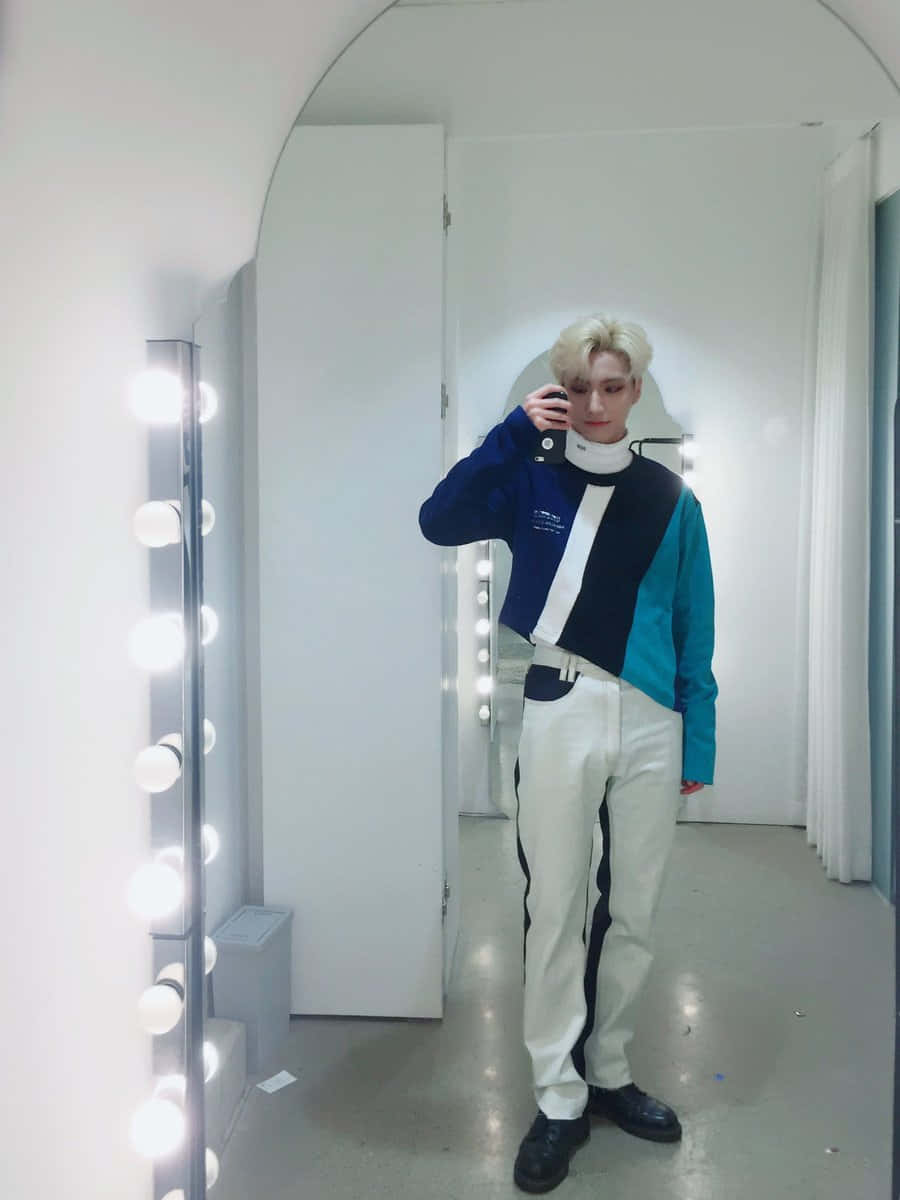 酷炫燈光鏡前自拍 壁紙 — 一位擁有鉑金色頭髮嘅人喺光猛嘅 dressing room 入面，對住一塊有垂直燈條嘅鏡影 selfie。
