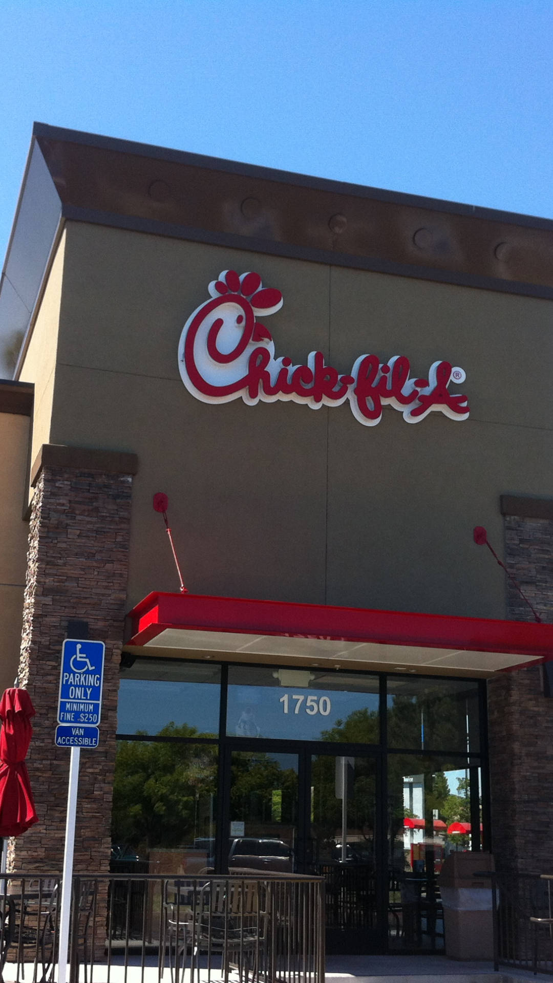 酷炫的 Chick Fil A 標誌招牌 壁紙 — Chick-fil-A 餐廳建築在晴朗藍天下，紅色遮陽篷和殘疾人士停車標誌清晰可見。