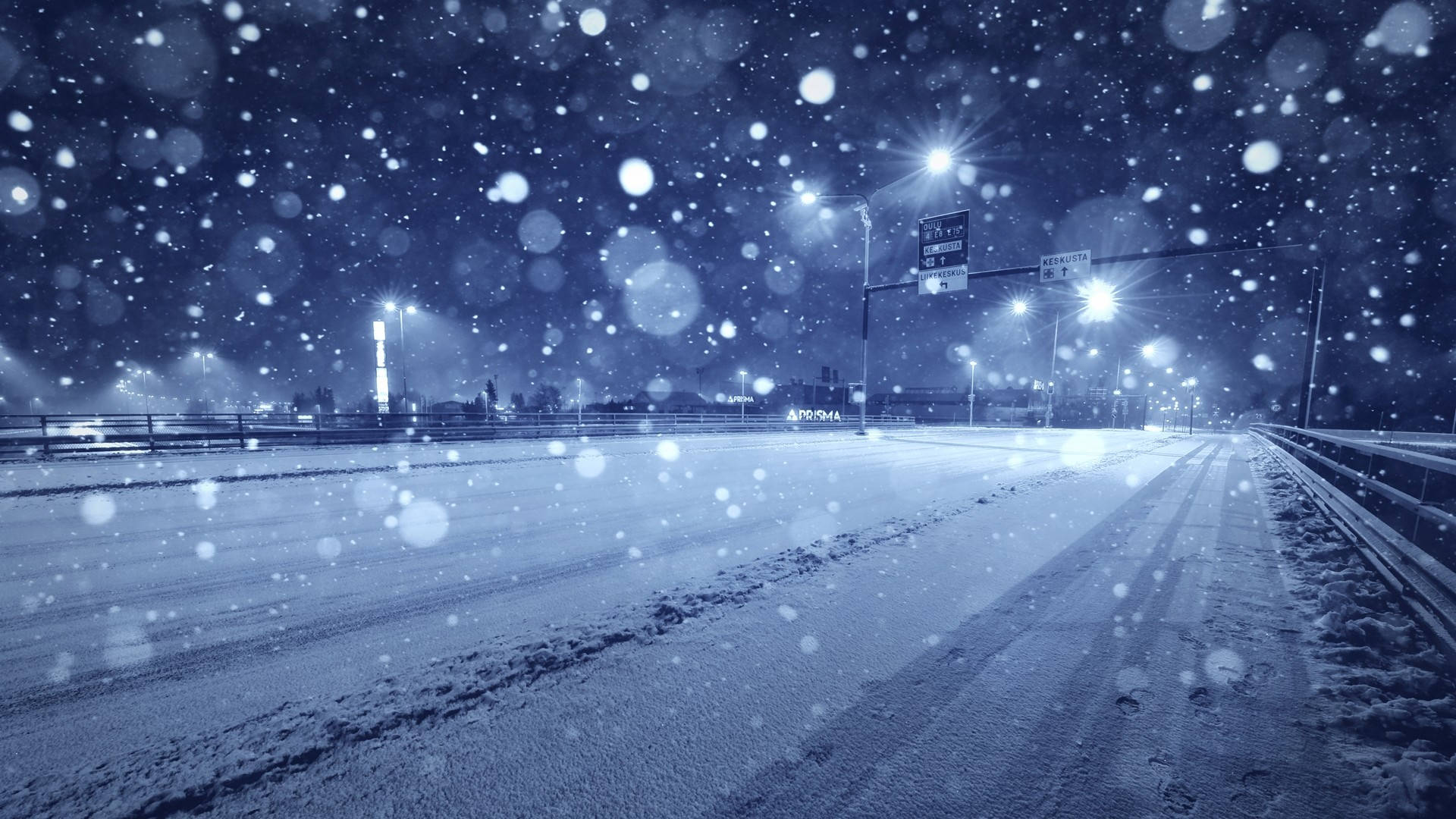 夜晚，雪花飄落在由街燈照亮的黑暗高速公路上。