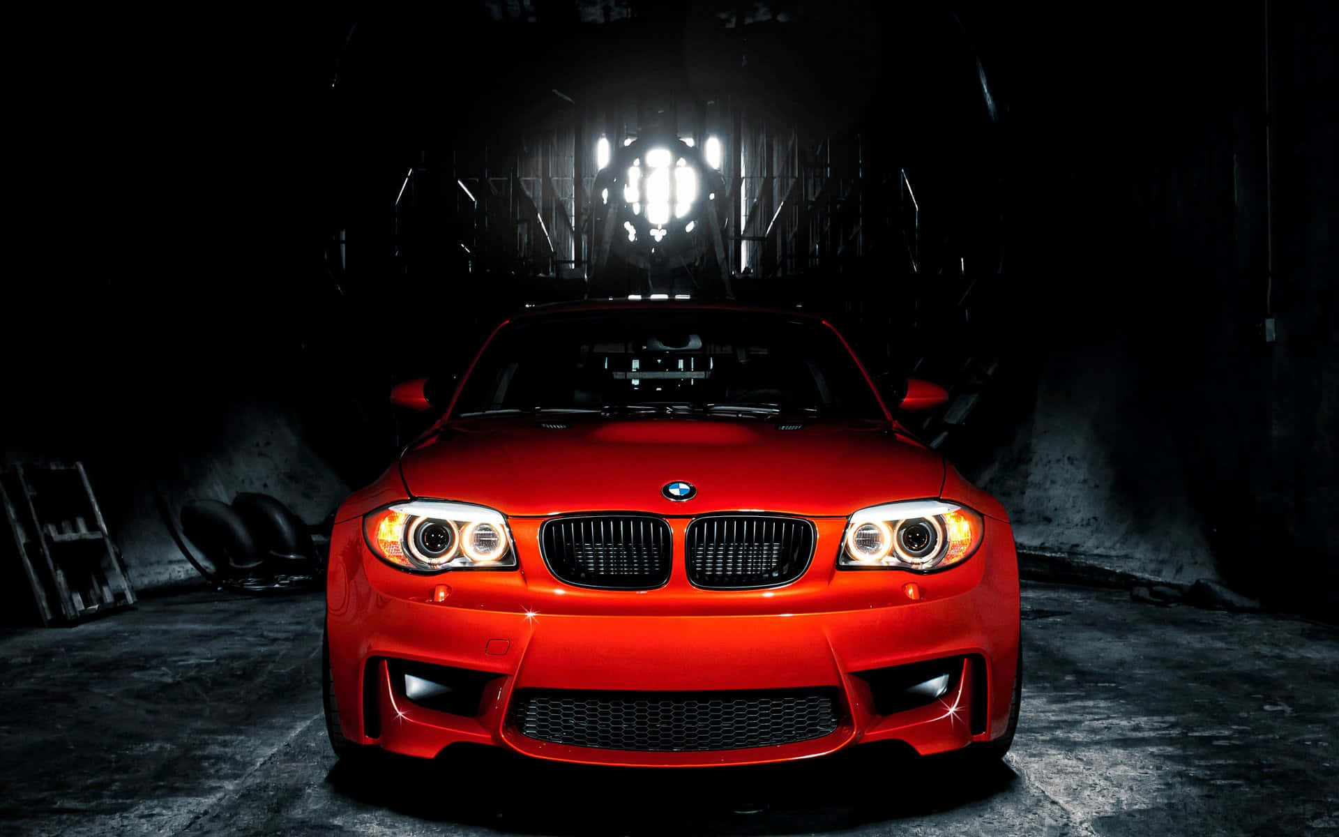 在黑暗的工業車庫中照亮的紅色BMW跑車。