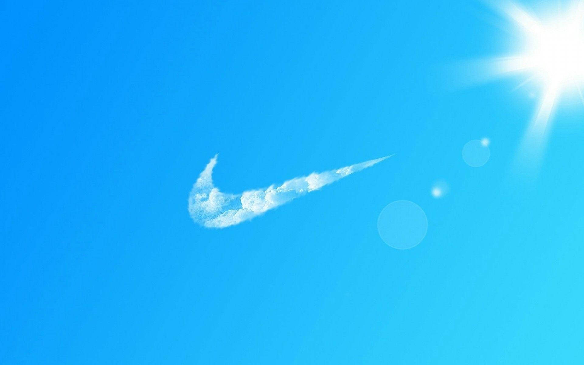 酷炫耐克雲朵 壁紙 — 明亮的藍天中，一朵白色雲朵形狀像Nike的勾號，右上角有耀眼的太陽。