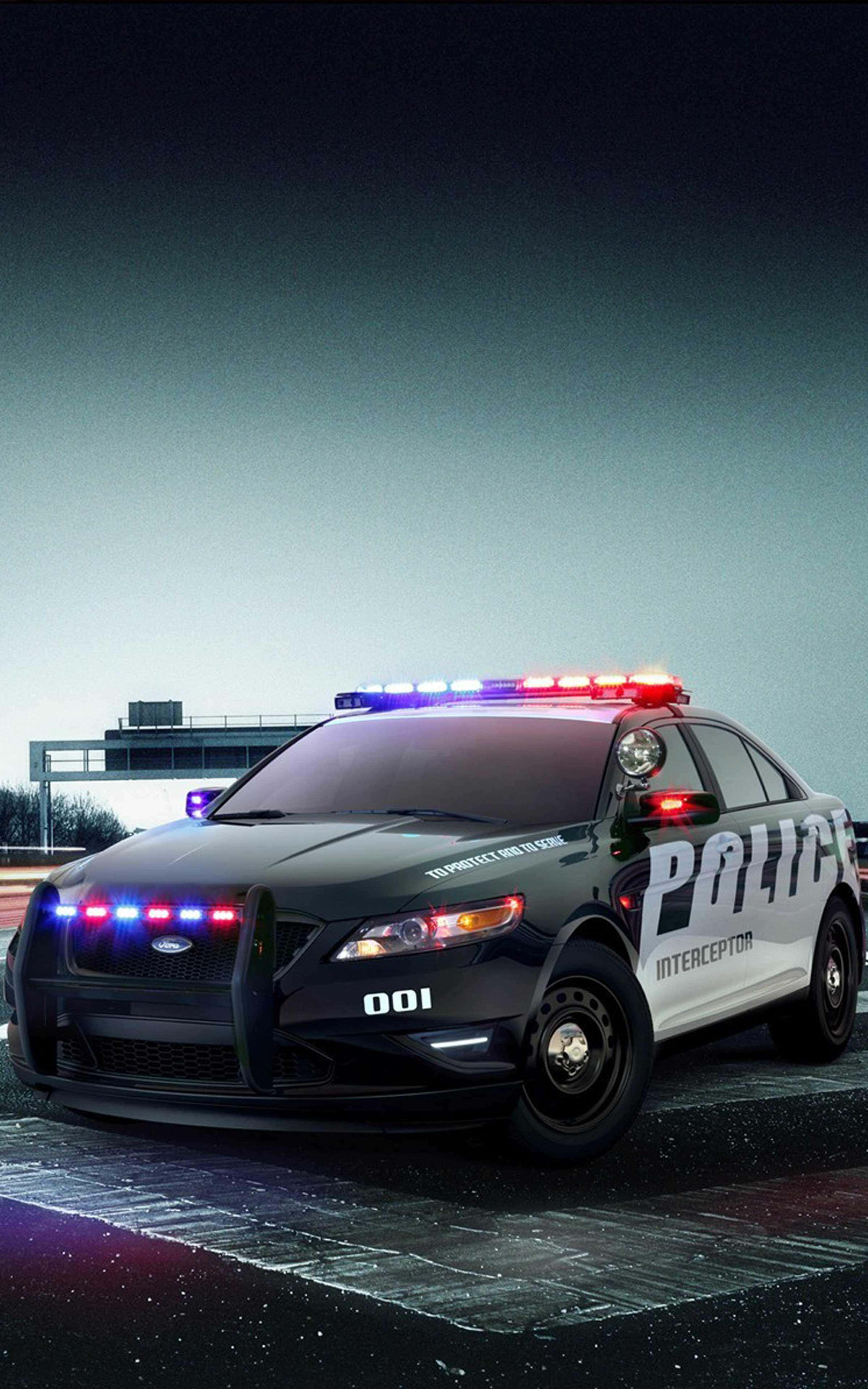 酷炫警車最佳汽車背景 壁紙 — 一輛黑白警用攔截車，帶有閃爍的紅色和藍色燈光，夜間停在潮濕的道路上。