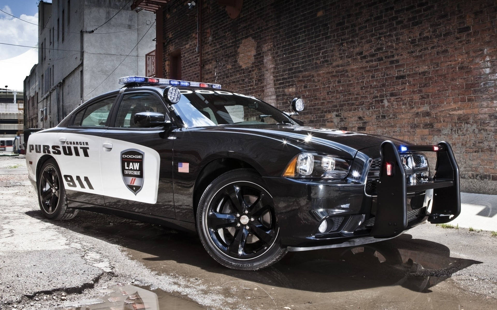 黑白警車停在磚牆附近的濕路面上。