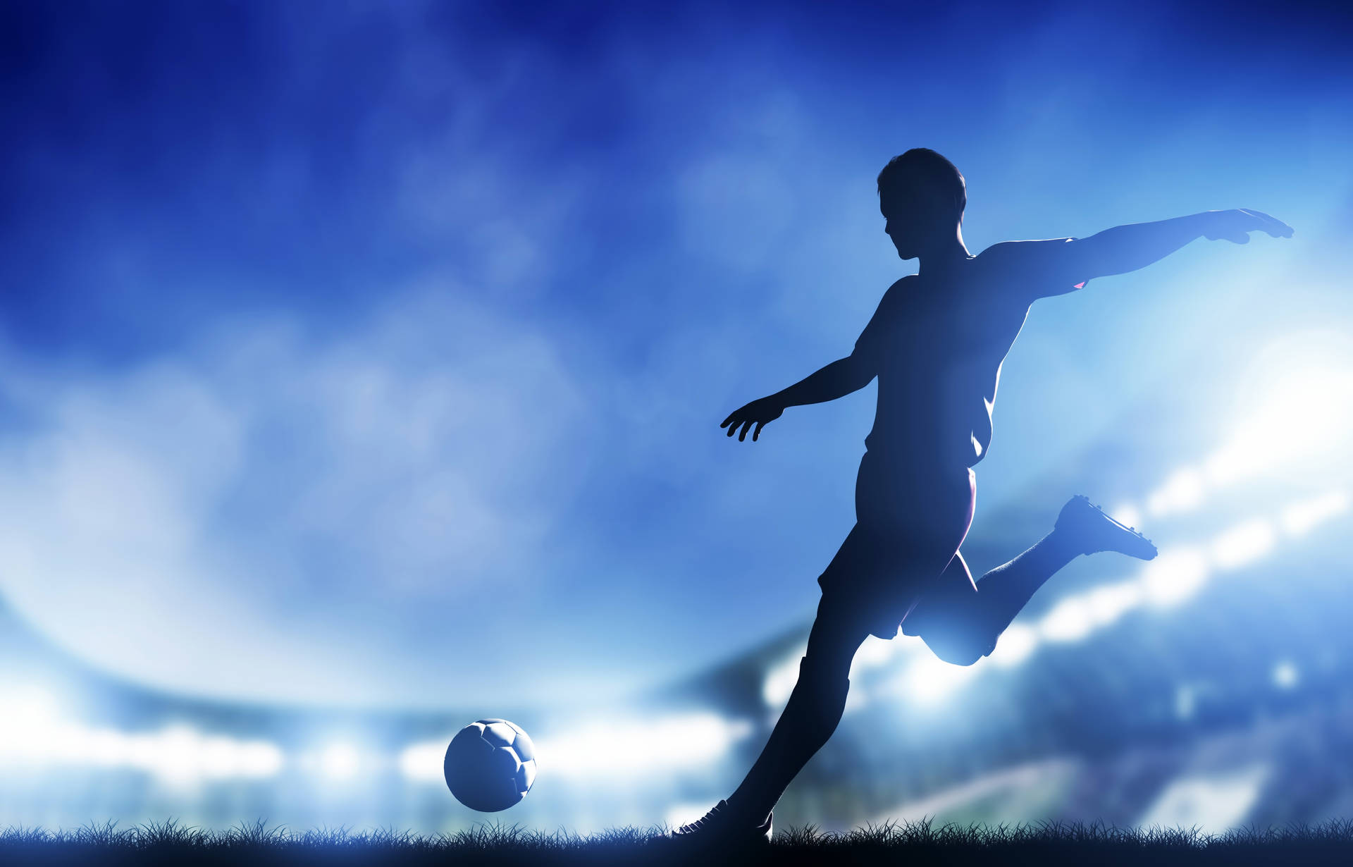 足球運動員在夜間體育場藍色燈光下踢球。