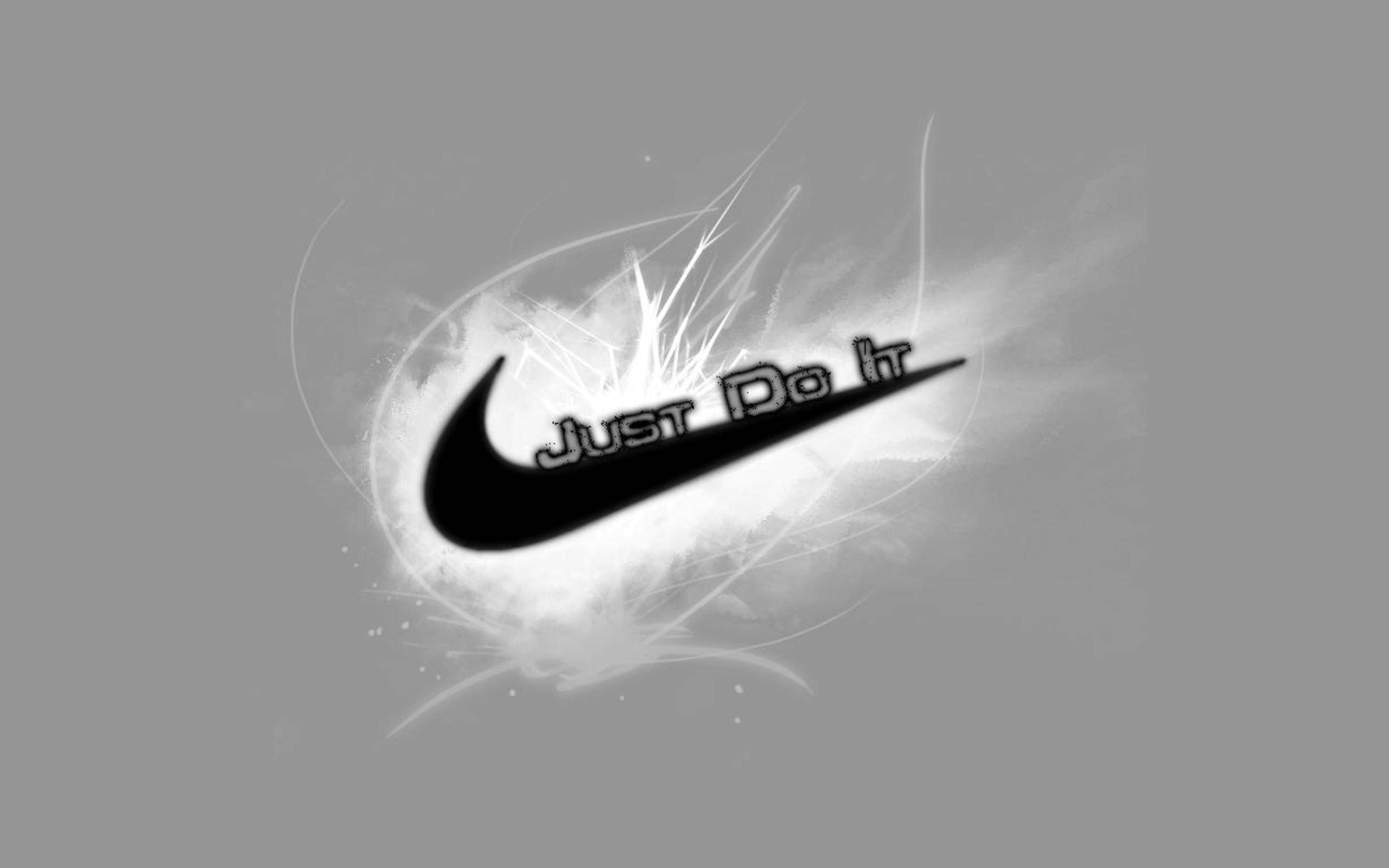 酷炫黑白耐克 壁紙 — 一個大膽的黑色Nike剔號配上「Just Do It」文字，從灰色背景上的動態白色能量爆發中浮現。
